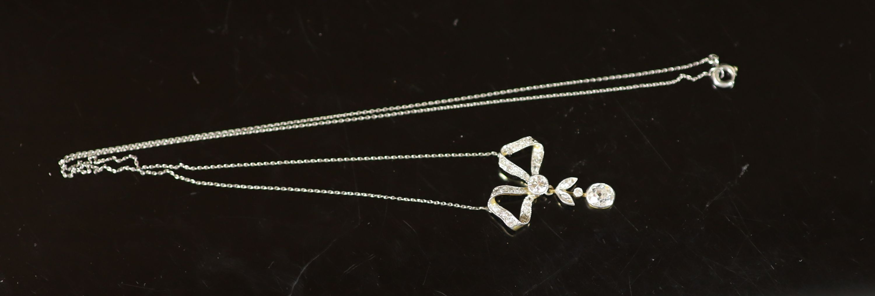 An early 20th century gold, platinum and diamond set drop ribbon bow pendant necklace
